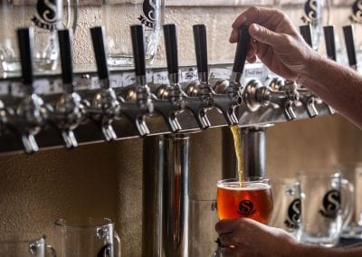 Satire Brewing Company Denver, CO- Man pouring beer into glass.
