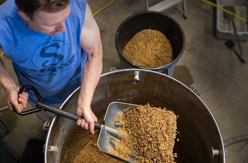 Brewing Beer Denver, Colorado- Owner putting hops in beer barrel