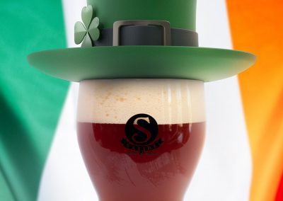 Beer with a leprechaun hat and an Irish flag in the background